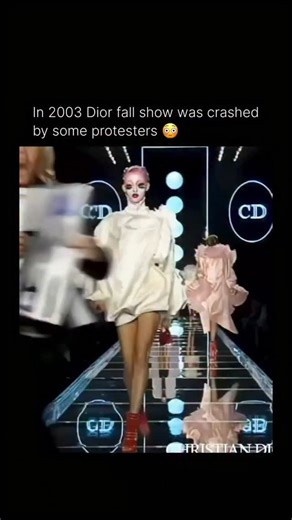 Celeb source TV on Instagram: "The 2003 Dior Fall-Winter ready-to-wear show in Paris, under then-creative director John Galliano, was famously crashed by an animal rights activist. A female protester from PETA (People for the Ethical Treatment of Animals) abruptly jumped onto the catwalk, disrupting the presentation. She carried a sign that read “FUR SHAME” and chanted against the use of animal fur in fashion. Security quickly intervened and forcefully removed her from the runway. The incident w