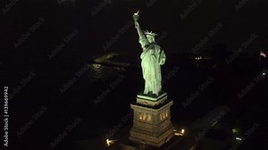 AERIAL HELI SHOT CLOSE UP Flying around Lady Liberty enlightening the world majestic sculpture. Statue of Liberty National Monument on Liberty Island in New York lit up with lights shining in the dark
