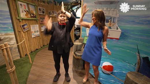 Jimmy Buffett’s spirit lives on at Latitude Margaritaville—even in the way neighbors say hello. Chief Marketing Officer Tamara Baldanza-Dekker shows Martha Teichner the unofficial Parrothead greeting, straight from Buffett’s hit song “Fins.” | CBS Sunday Morning