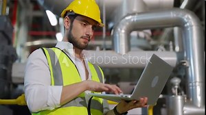 Professional male electrical engineer working on laptop computer at factory site control room. Industrial technician worker maintenance and checking power system at manufacturing plant room. Stock Video