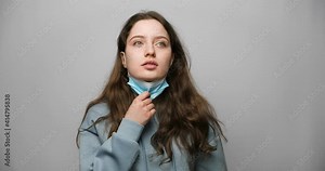 The girl takes off her medical mask and takes a breath. Takes off the mask incorrectly.