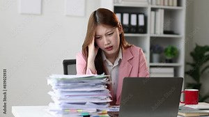 Serious businesswoman doing paperwork in the office is stressed due to excessive workload. Asian woman who is overworked, she is stressed and has a headache.