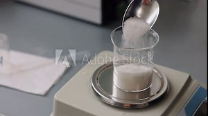Sugar measurement, digital scale, laboratory accuracy. Sugar being measured in glass beaker on digital scale in laboratory setting.