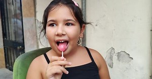 Girl Enjoys a Lollipop While Sitting Outside