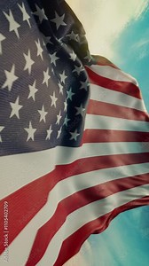 Wavy flag of United States of America blowing in the wind in slow motion. Waving official USA flag team symbol abstract vertical background. Blue sky with clouds. World countries flying flags concept