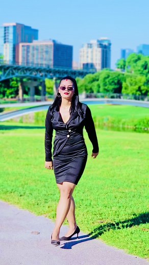 Confident Woman in Black Dress Walking in Park