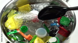 Global pollution and ecological damage concept. Abstract view of environmental degradation and animal suffering. Stirring through pan of 'plastic soup' with floating litter.
