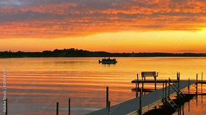 Beautiful Lake Irving in Bemidji Minnesota, the first lake on the Mississippi River, is seen at sunset as a pontoon with fishermen floats past a boat dock on a calm evening.