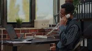 Office worker using landline phone to answer business call, discussing abput commercial strategy and innovation. Employee talking on telephone while he works on company development.