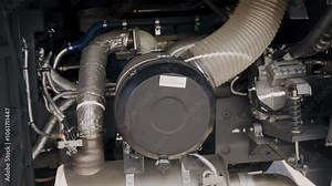 A close-up look at the intricate air filter and muffler components within a bus engine. Observing the detailed assembly showcases the technology behind efficient engine airflow and sound management.