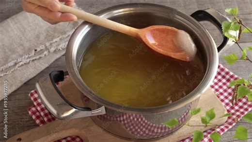 Making homemade dandelion syrup or honey - stirring sugar in water in which fresh dandelion flowers have been macerated