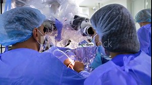 Approaching the doctors looking at neuro microscope. Rear view of neurosurgeons performing procedure. Close up.