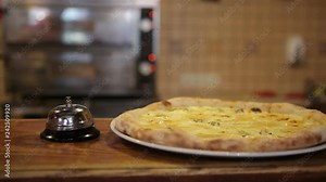 The chef pizza maker rings the bell at the bar, the cook gives a signal to the waiter that the pizza order is ready.