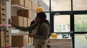 Warehouse operation executive and worker preparing orders for delivery, receiving phone call from management with new instructions in stockroom while scanning labels on parcels to be shipped