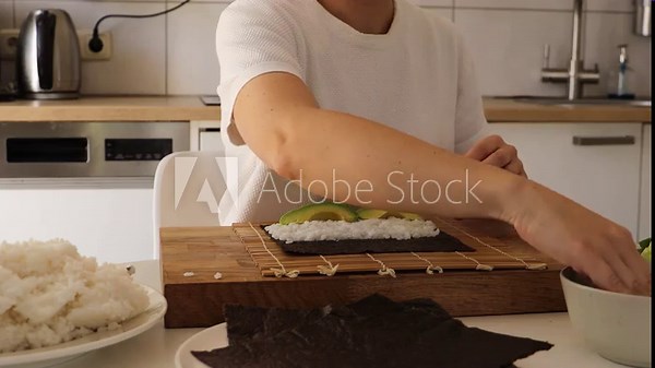 In this engaging tutorial, a woman demonstrates the art of sushi-making at home, skillfully preparing rice and rolling sushi with precision. Discover simple techniques to enjoy fresh sushi