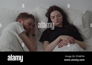 A married couple sleeps on the bed, but the wife wakes up from the sound of the alarm clock and wakes up the husband. Video in which a married couple wakes up due to the alarm clock going off. High Stock Video Footage - Alamy
