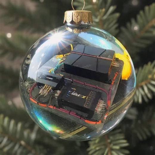 Restyle the image so that it appears as a reflection inside a shiny Christmas ornament. Curve and warp the scene naturally to match the rounded reflective surface, adding bright highlights, glossy shine and metallic colour tones from the ornament. Keep the subject's face, pose, clothing and expression recognisable, but viewed through the curved reflection. Replace the background with the close-up view of the ornament surface and a soft hint of a Christmas tree behind it. Do not show the original