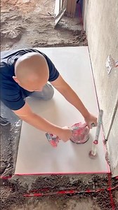 Worker placing floor tile precisely using laser alignment tools