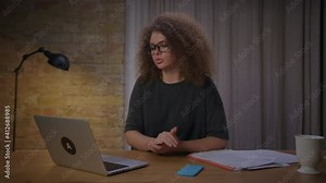 Young female teacher speaking to laptop explaining to pupils new material. 20s woman has online lesson working from home.