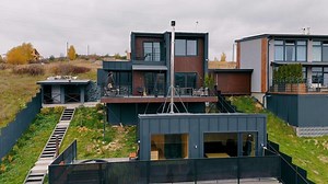 Modern Hillside Home with Balconies and Patio Space. A contemporary hillside home featuring a multi-level design with wooden and metal accents, spacious balconies, a patio area, and a rooftop lounge.