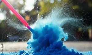 A burst of blue powder erupts from a surface, creating a vibrant splash effect.