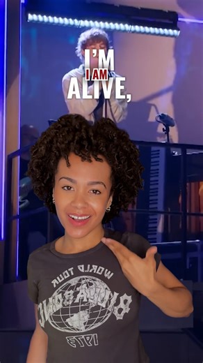 Next to Normal in ASL just hits different 💜 — VID: Kaia T. Fitzgerald, wearing a dark grey t-shirt, uses American Sign Language to sign the lyrics to I'm Alive from the musical Next to Normal. Captions for both the spoken and signed lyrics appear on-screen above Kaia's head, while footage of Jack Wolfe singing the song plays in the back. | Deaf West Theatre