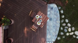 Viewing a table set for breakfast from a high vantage point (aerial drone shot moving upwards), situated at a nature-immersed resort.