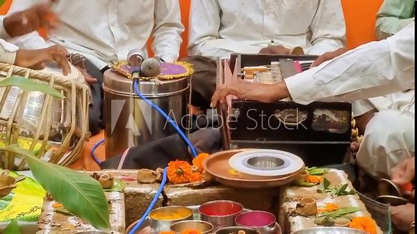Hindu Puja: A worship ritual performed by Hindus for devotion, honoring guests, or celebrating events. Scene shows typical setup with essential elements and instruments like tabla and harmonium. Stock Video