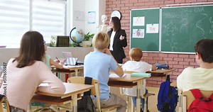 Cheerful Caucasian young female teacher of anatomy or biology talking to class and explaining human DNA to pupils. At school. Education concept. Indoors. Teaching. Lection about body.