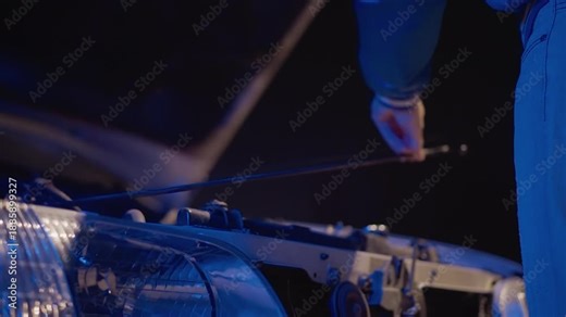 Mechanic fixing engine near street, Urban roadside scene with mechanic adjusting car components, Streetside automotive repair with technician working under vehicle headlights and urban setting Stock Video