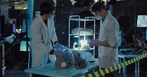 Doctors spend experience on an alien on a spaceship. Humanoid is connected to a respirator and lies on an operating table.
