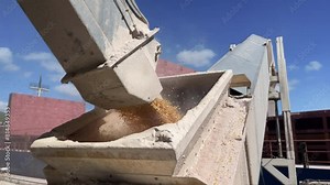 Grain trade, delivery by dry cargo ship by sea. Low angle close up silo belt loading Ship with grain corn or weat