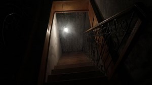 Creepy wooden stairs going down to the Basement in an abandoned house. Swinging bulb. Horror Halloween concept. Gimbal Steady cam shot