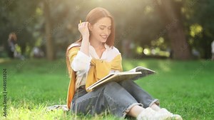 Beautiful busy girl preparing for exam studying and reading notebook at green park Pretty student make notes while having distance remote education outdoors
