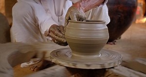 Skilled wet hands of potter shaping the clay on potter wheel and sculpting vase. Manufacturing traditional handmade Indian bowl, jar, pot, jug. Shilpgram, Udaipur, Rajasthan, India