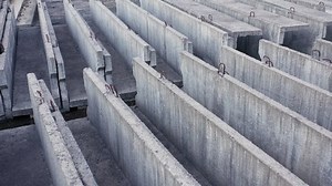 Precast concrete beams on the construction site. Project development of an industrial hall, factory or commercial building. Engineering of reinforced and prestressed elements of a structure.