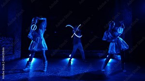 Light LED dance show. Impressive dances of two beautiful girls in dresses with glowing LED flashlights in their hands and a guy with LED knives. Smooth camera zoom