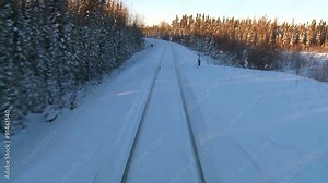 POV from the front of a train passing through a snowy landscape.