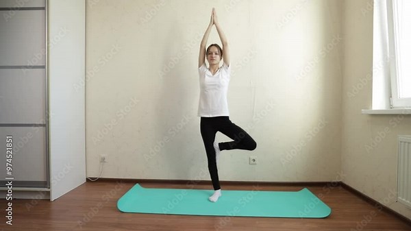 Teenage girl doing yoga at home, learning new yoga poses and techniques, balancing body and mind, and embracing a healthy and fit lifestyle.