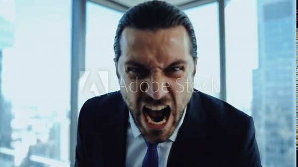 Angry businessman screaming at the camera while holding papers in a modern office. Furious boss yelling and shaking documents in a fit of rage. Corporate stress and conflict concept