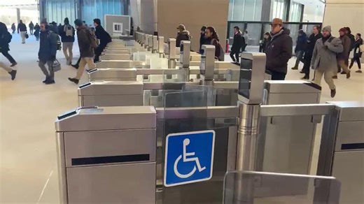 Boston commuters seen walking through open fair gates at South Station