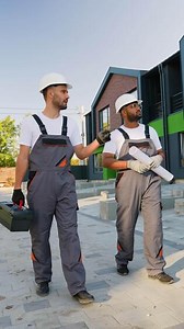 Two Builders Walking Near Modern Townhouse Construction