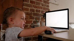 Smiling cute little girl using laptop close up, looking at screen, watching video or cartoons, sitting at table, having fun with gadget alone, electronic device addiction