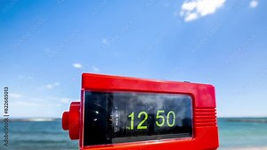 flip clock with time passing on a beach with sky and sea in background
