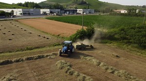 Tractor Machine Working on Hay Bales in Agriculture Field