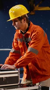 Vertical Agitated oil rig inspection officer evaluates fuel production systems and sweating, working in tension to ensure petroleum compliance and natural fuel extraction. Concerned engineer. Camera B.