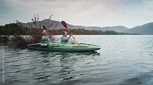 Elderly women kayaking on the lake. Two senior women paddle kayak on the calm lake and explore the coast with mangrove trees