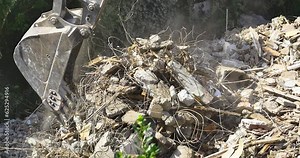 Backhoe excavator clearing up the area after the demolition. Bulldozer works to get rid of the rubbish for formation of the land at the construction site. Crawler excavator lifting up scrap rebars Stock Video