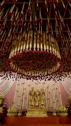 Vivahhika on Instagram: "An ode to rare treasures, this wedding decor is a tribute to the legendary Meenakshi thirukalyanam, envisioning traditional aesthetic subsumed in white, red and gold. The decor is inspired by the divine union of the fish eyed goddess Meenakshi and Lord Sundareswarar, a sight to behold with a glacial array of champaki and rose strands in concentric circles beneath which the bride and groom take eternal vows of love. The mandap design is made luxurious by a gulf of pond pa