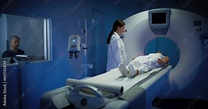 High-Tech Modern Medical Equipment: In Medical Laboratory Male Radiologist and Female Doctor Control and Monitor MRI or CT Scan with Female Patient Undergoing Health Procedure